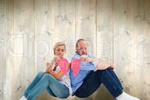 Composite image of sad mature couple holding a broken heart