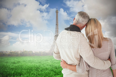 Composite image of happy couple standing with arms around