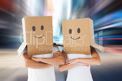 Composite image of couple wearing smiley face boxes on their hea