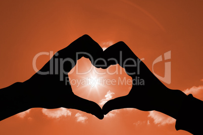 Composite image of couple making heart shape with hands