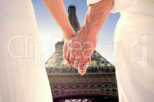 Composite image of bride and groom holding hands close up