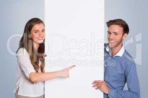 Composite image of happy young couple with blank board