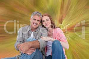Composite image of casual couple sitting and smiling