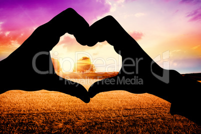 Composite image of couple making heart shape with hands