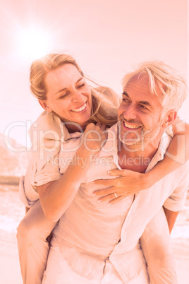 Man giving his smiling wife a piggy back at the beach