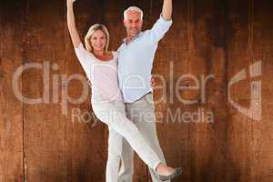 Composite image of smiling couple cheering at the camera