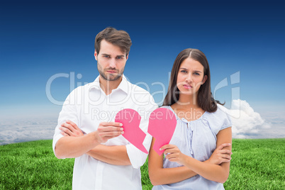 Composite image of upset couple holding two halves of broken hea