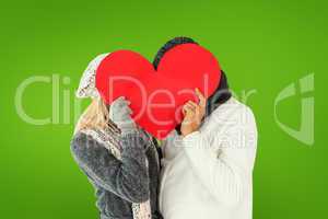 Composite image of couple in winter fashion posing with heart sh