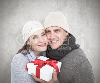 Composite image of casual couple in warm clothing holding gift