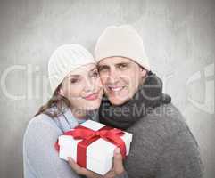 Composite image of casual couple in warm clothing holding gift