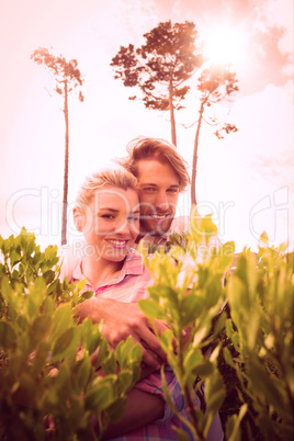 Smiling couple embracing outside among the bushes