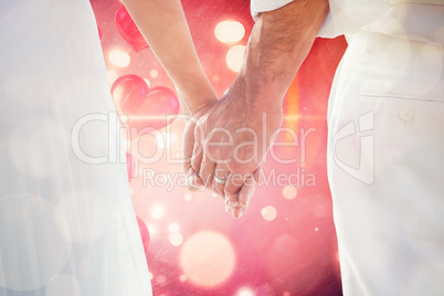 Composite image of bride and groom holding hands close up