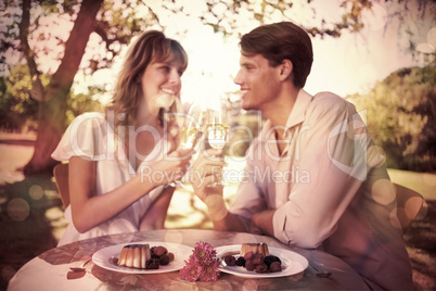 Cute happy couple sitting outside toasting with champagne with d