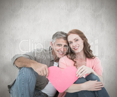 Composite image of casual couple holding pink heart