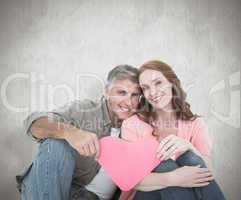 Composite image of casual couple holding pink heart