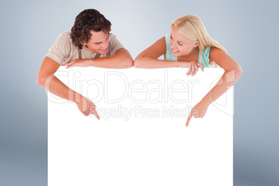 Composite image of handsome man and woman pointing on a whiteboa