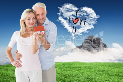 Composite image of happy couple holding miniature model house