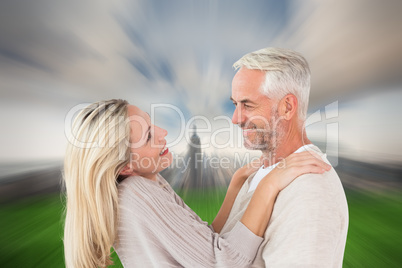 Composite image of happy couple standing and hugging