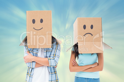 Composite image of young couple wearing sad face boxes over head