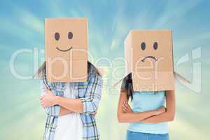 Composite image of young couple wearing sad face boxes over head