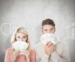 Composite image of attractive couple flashing their cash