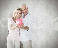 Composite image of happy couple showing their piggy bank