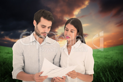 Composite image of attractive young couple reading their bills