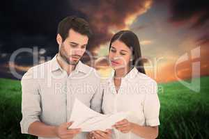 Composite image of attractive young couple reading their bills