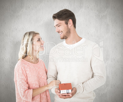 Composite image of attractive couple holding miniature house mod