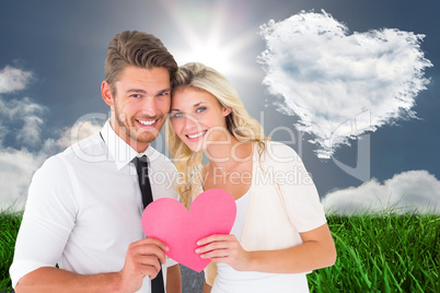 Composite image of attractive young couple holding pink heart