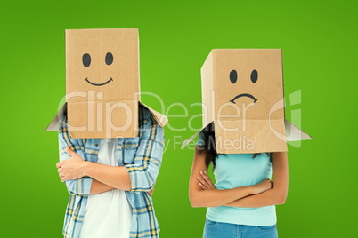 Composite image of young couple wearing sad face boxes over head