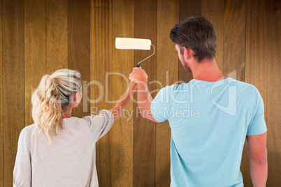 Composite image of young couple painting with roller