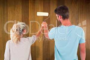 Composite image of young couple painting with roller