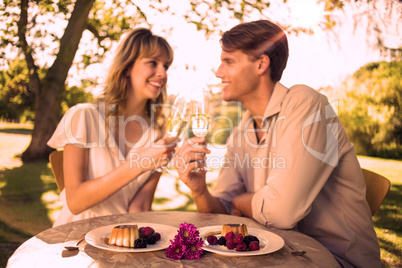 Cute happy couple sitting outside toasting with champagne with d