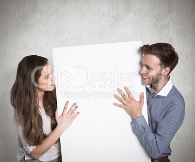 Composite image of happy young couple with blank board