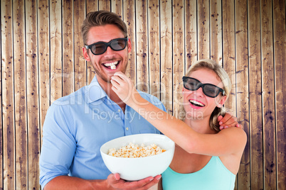 Composite image of happy young couple wearing 3d glasses eating