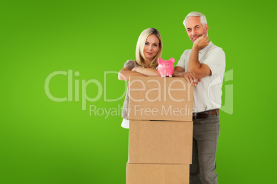 Composite image of happy couple leaning on pile of moving boxes