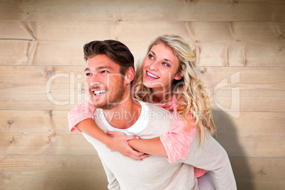 Composite image of handsome man giving piggy back to his girlfri