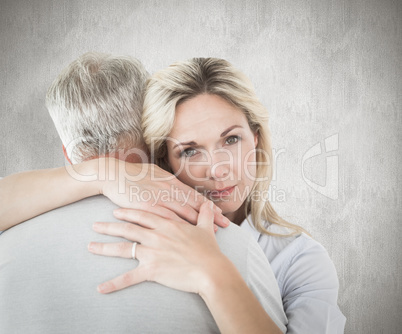 Composite image of unhappy blonde hugging her husband