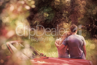 Loving couple admiring nature while leaning on their cabriolet