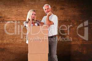 Composite image of happy couple leaning on pile of moving boxes