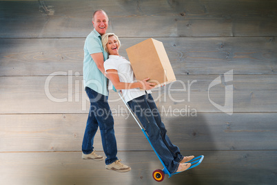 Composite image of fun older couple holding moving boxes