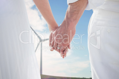 Composite image of bride and groom holding hands close up