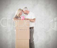 Composite image of happy couple leaning on pile of moving boxes