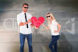 Composite image of cool young couple holding red heart