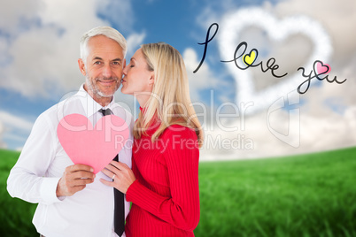 Composite image of handsome man holding paper heart getting a ki
