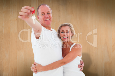 Composite image of mature couple smiling at camera with new hous