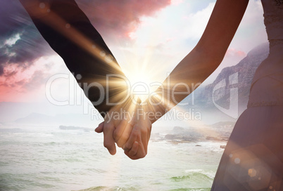 Composite image of mid section of newlywed couple holding hands