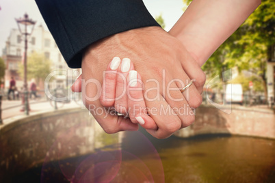 Composite image of newlyweds holding hands close up