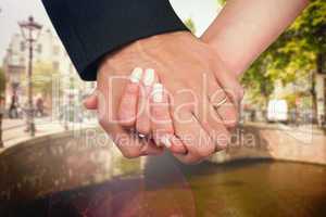 Composite image of newlyweds holding hands close up